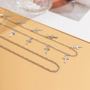 Detailed close-up of silver double-layered snake chains with metal cross pendants