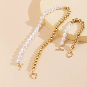 Détail du collier de perles et billes dorées avec fermoir en T et pendentif cœur