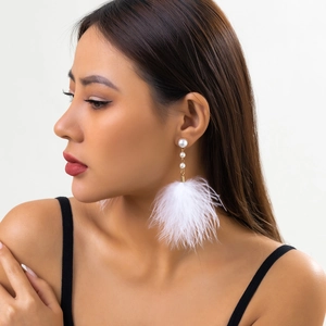 Detailed view of long elegant earrings with white feathers and faux pearl accents