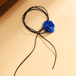 Detailopname van een handgemaakte donkerblauwe satijnen roos aan een zwarte suède choker