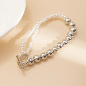 Détail du collier de perles et billes argentées avec un fermoir OT en métal élégant