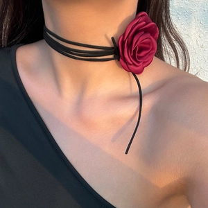 Detailopname van de fluwelen rozenchoker met zwarte touwtjes om de nek