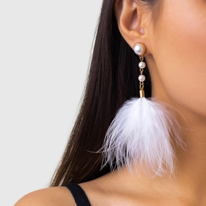Detail of elegant feather tassel earrings with pearls and gold chains on a model