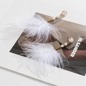 Detailed shot of elegant feather and pearl drop earrings with gold-tone hardware