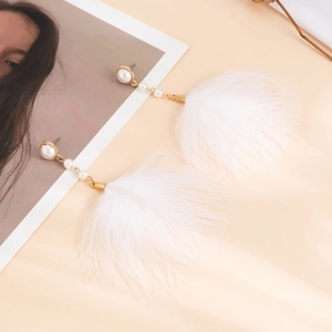 Detail of elegant white feather tassel earrings with faux pearl stud on silk fabric