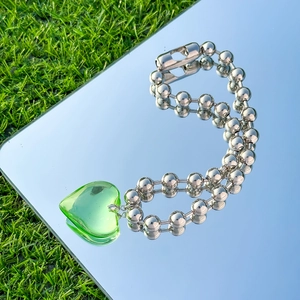Close-up of a silver beaded heart pendant necklace reflecting a blue sky on a mirror