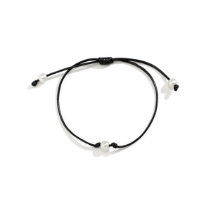 Detalle de la pulsera de cordón encerado negro con tres perlas blancas y nudos corredizos