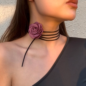 Detail van een handgemaakte dieppaarse satijnen roos choker op de hals bij warm licht