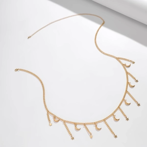 Detail of golden waist chain featuring celestial star and moon fringe pendants with lobster clasp