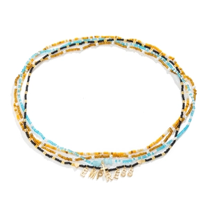 Detail of colorful beaded body chain with gold Empress letters, cross, and heart charms
