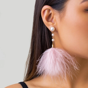 Detailed shot of long tassel earrings with pearls and soft pink feather pom poms