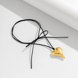 Detail of a gold fluid heart pendant on a black adjustable cord necklace in close-up