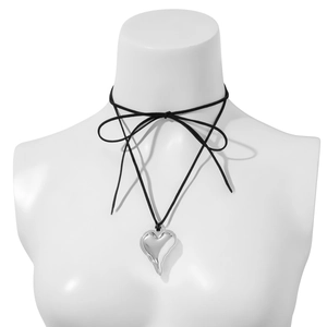 Detail of a large silver heart pendant on a black cord choker tied in a bow