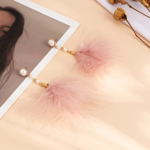 Detail of vintage gold earrings with white pearls and soft pink feather tassels