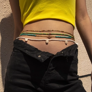 Detail of layered boho waist beads with colorful seed beads and natural cowrie shell pendants