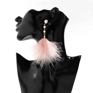 Detail of pink feather tassel earrings with white pearls on a black mannequin
