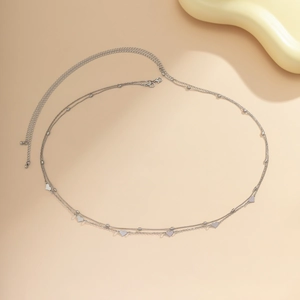 Detailed view of a layered silver body chain with small heart pendants and adjustable clasp