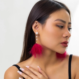 Close-up of elegant rose red feather tassel earrings with white pearls on a female model