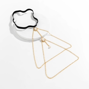 Detail of a black elastic leg chain with layered gold chains and white pearl charms