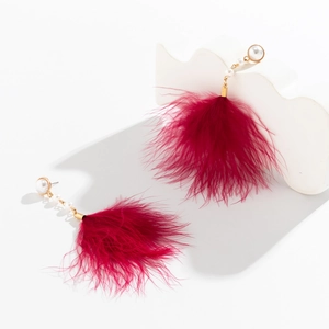 Detail of vintage gold earrings with large white pearls and rose red feather tassels