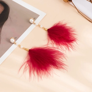 Detail of elegant red feather tassel earrings with faux pearls on gold alloy chains
