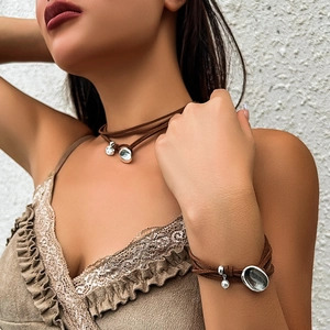 Detail van de bohemian choker en armband van bruin suède met zilveren hangers en parels