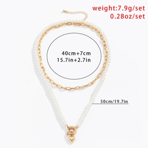 Détail du collier à deux rangs avec chaîne trombone dorée, perles et pendentif cœur