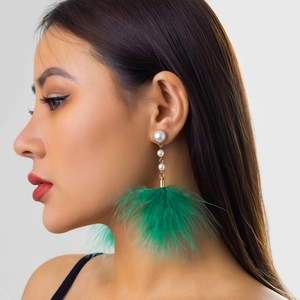 Close-up of green feather tassel earrings with white pearls on a female model
