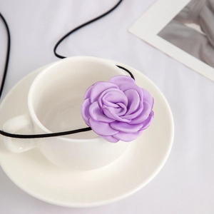 Detailopname van de paarse satijnen roos choker over een witte porseleinen koffiekop