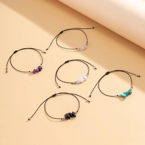 Detalle de cinco pulseras ajustables de cuerda negra con varias perlas de piedra natural
