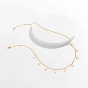 Detail of elegant gold chain thigh leg harness featuring white pearls and lobster clasp