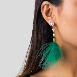 Close-up of elegant feather fringe earrings with white pearls and green plumage detail