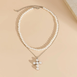Détail d'un collier double rang avec perles blanches et pendentif croix en perle