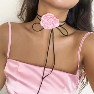Detailopname van roze satijnen roos choker met zwart lint om een vrouwelijke nek