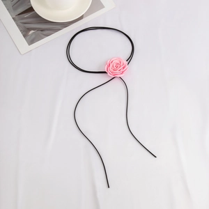 Detail van een 3D roze stoffen roosbloem aan een lange zwarte fluwelen choker
