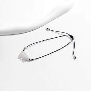 Detalle de tobillera de cordón negro ajustable con piedras turquesas y cuentas de plata