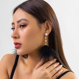 Detail of feather tassel earrings with white pearls and gold metal on female model