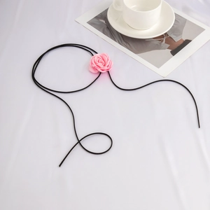Detailopname van roze fluwelen rozenchoker met verstelbaar zwart koord op witte stof