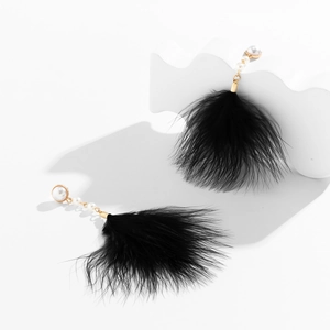 Close-up of elegant black feather earrings with white faux pearls and gold chain links
