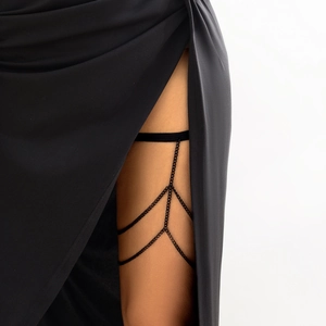 Close-up of black layered metal thigh chain with elastic band on thigh under black dress