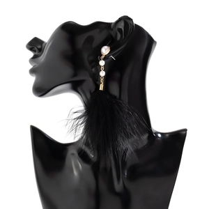 Detail view of long tassel earrings with black feathers and elegant white pearls