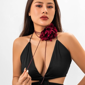 Detail of a large wine red silk flower choker necklace with long tassel straps on a model