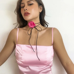 Detail van een rozerode stoffen bloemenchoker gestyled met een roze satijnen bandjurk