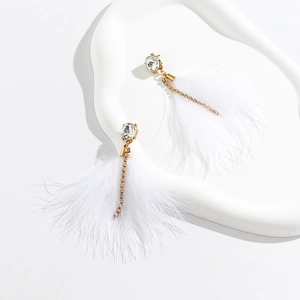 Detail of elegant gold feather earrings with sparkling rhinestones and white plumage
