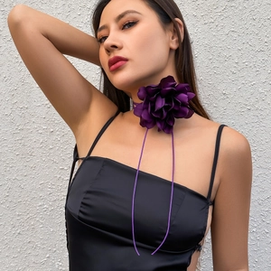 Detail of a dark purple oversized floral fabric choker with long adjustable ribbon ties