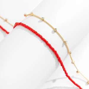 Detail of red beaded chain and gold finish link chain with sparkling square rhinestones