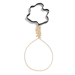 Detail of elastic thigh chain with golden metal leaves and delicate hanging chains