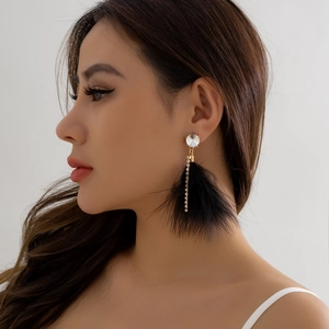 Detailed view of elegant long earrings with sparkling rhinestones and black feather tassels