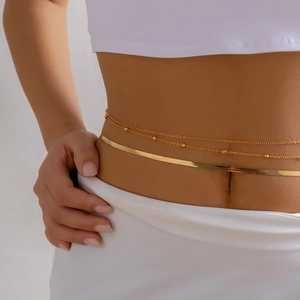 Detail of double-layer gold snake chain and beaded tassel waist chain on model