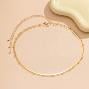 Detail of golden double-layer body chain featuring a flat snake chain and beaded texture